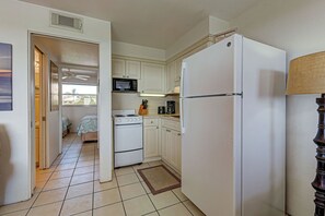 A compact kitchen with white cabinets, a refrigerator, a microwave, a stove, and a coffee maker. - Directly on the Gulf - Unit 13 - 1 Bedroom - Second Floor - Sleeps up to 4 (Venice)