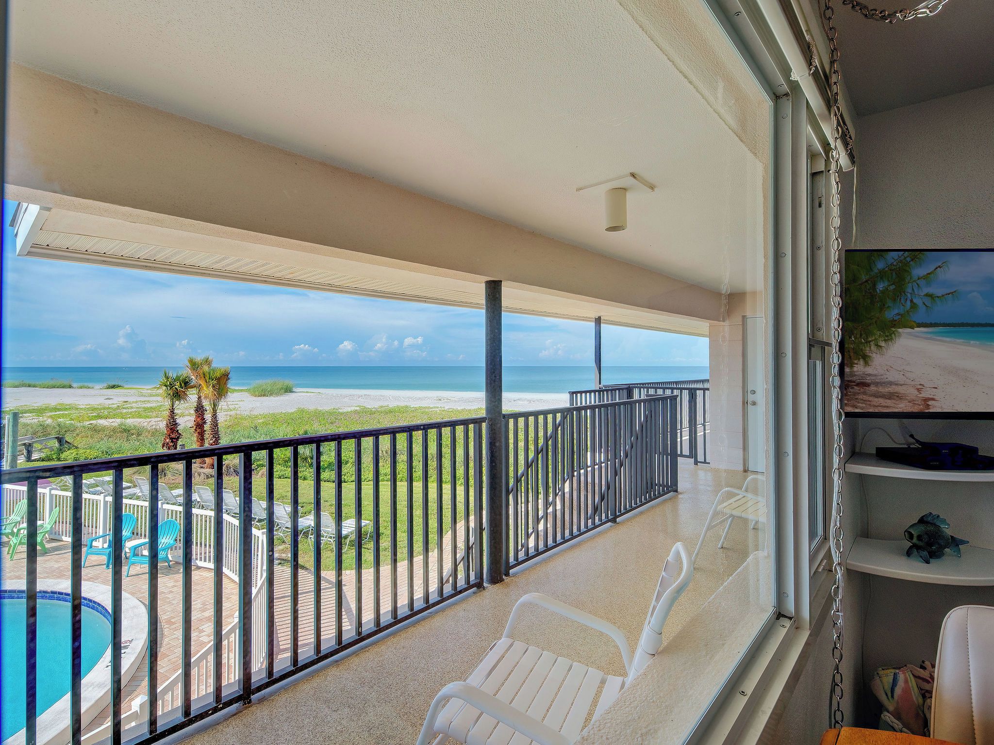 Un balcon avec vue sur une plage et une piscine.