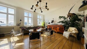 Relax in this stylish living room with a high ceiling, city views, and a comfortable leather armchair.