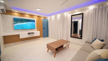 A modern living room with a TV, a wooden coffee table, a sofa, a ceiling fan, and a mirror.