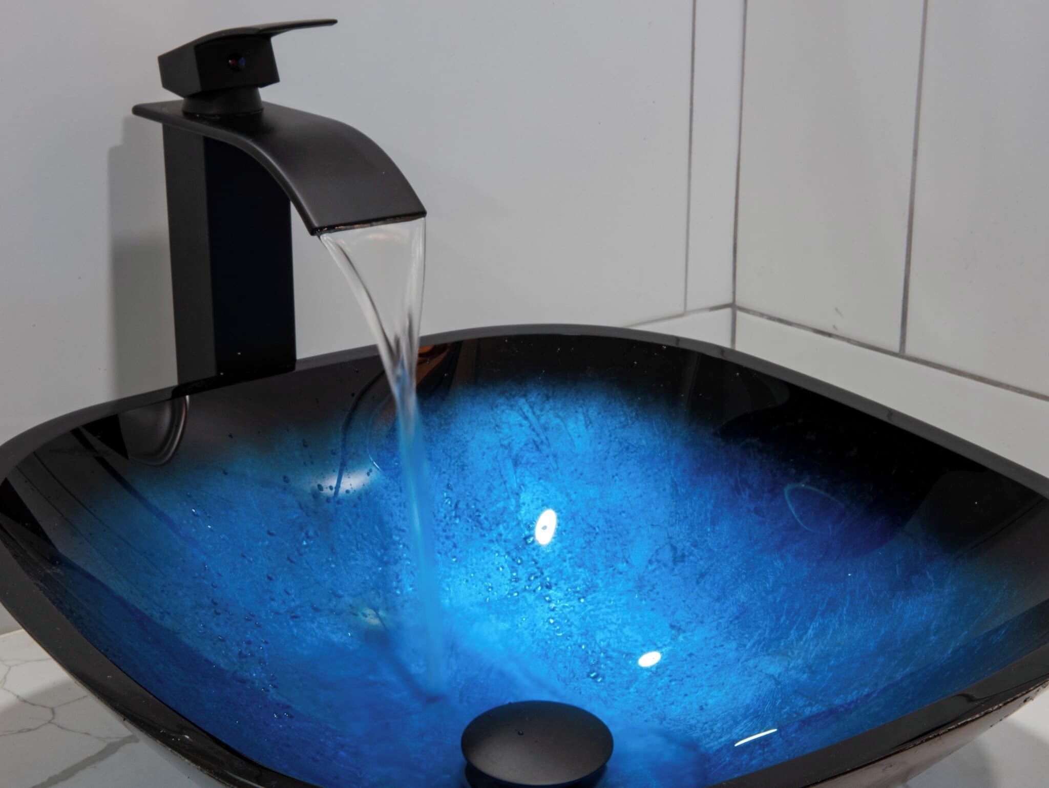 Un évier noir, de type «vaisseau», avec de l’eau qui coule du robinet.
