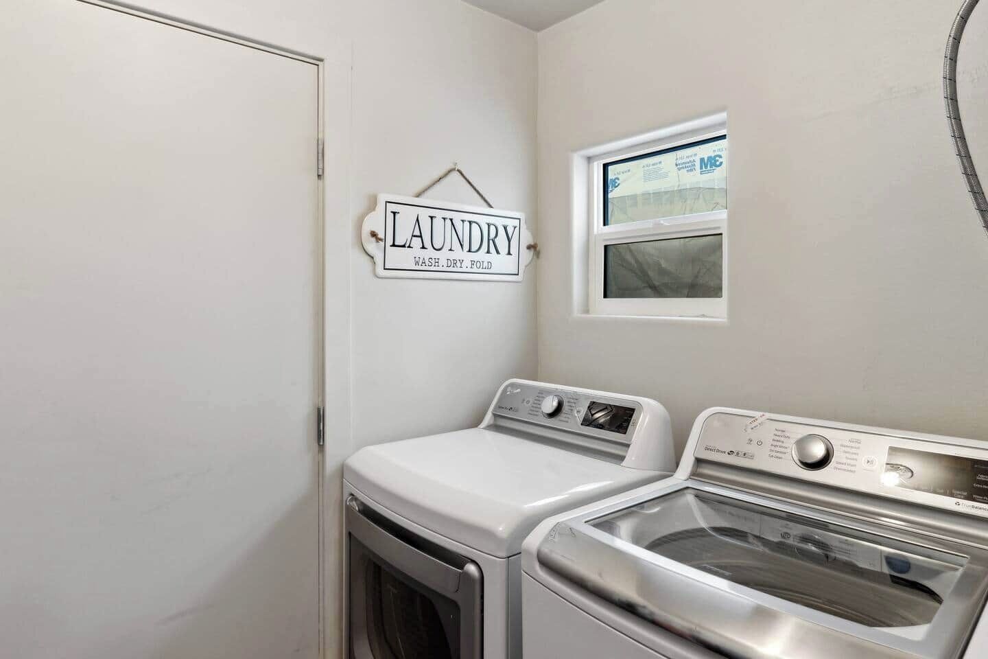 A laundry room with a sign reading "LAUNDRY WASH. DRY. FOLD" and two washing machines.