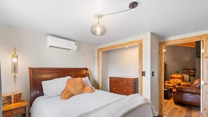 A bedroom with a wooden bed, a nightstand, a dresser, and a leather sofa in the adjacent living area. - The Bizarre and the Beautiful (Albuquerque)