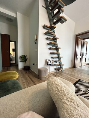 Una sala de estar moderna con una escalera, un sofá, una mesa de centro y una planta.
