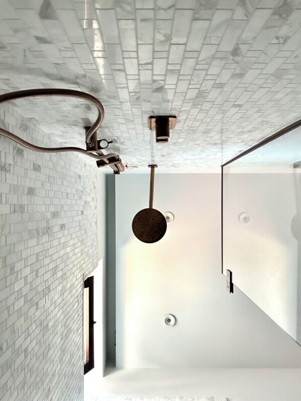 Un interior moderno con una pared de ladrillo blanco, una lámpara colgante y un espejo grande.