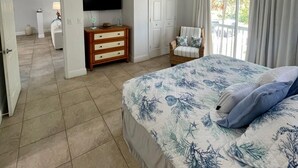 Ein Schlafzimmer mit Bett, Deckenventilator, Fernseher, Kommode und Stuhl.