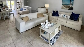 Ein geräumiges Wohnzimmer mit weißem Sofa, Couchtisch und Deckenventilator.