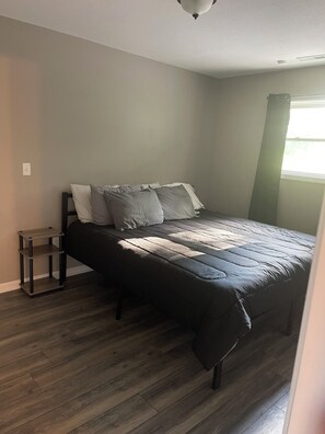 Cozy retreat with a comfortable bed, nightstand, and natural light.