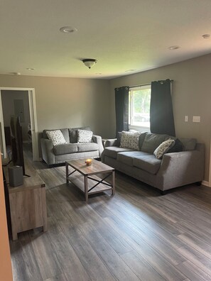 Relax in this stylish living room with two sofas, a coffee table, and a TV on a stand.
