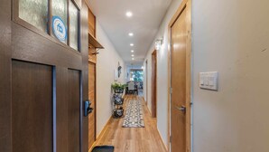 Un couloir avec des portes en bois, un tapis à motifs et des spots encastrés au plafond.