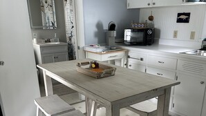Ett kök med vita skåp, ett träbord och en bänk.