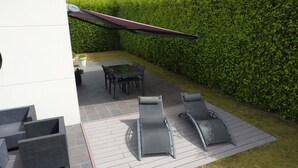 A patio with a table and chairs, a lounge chair, and a pergola. - Maison 2 à 8 Personnes Plurien - Sables D'or les Pins, à 800 m de la Plage (Plurien)