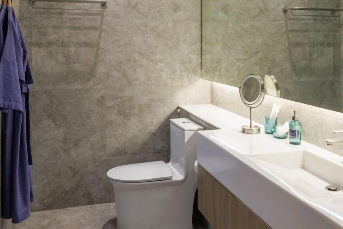 A bathroom with a toilet, sink, and mirror.