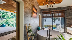 Un baño moderno con una bañera grande, techo de madera y vistas al exterior.