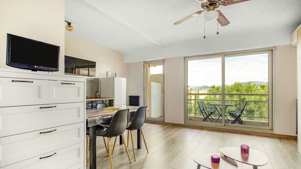 Ein geräumiges Zimmer mit Essbereich, einem an der Wand befestigten Fernseher und einem Balkon mit Blick.