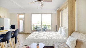 Ein Schlafzimmer mit Bett, einem kleinen Tisch, einem Deckenventilator und einem Balkon mit Stühlen.