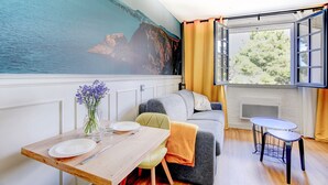 Ein gemütliches Zimmer mit Esstisch, einer Couch und Meerblick durch ein großes Fenster.