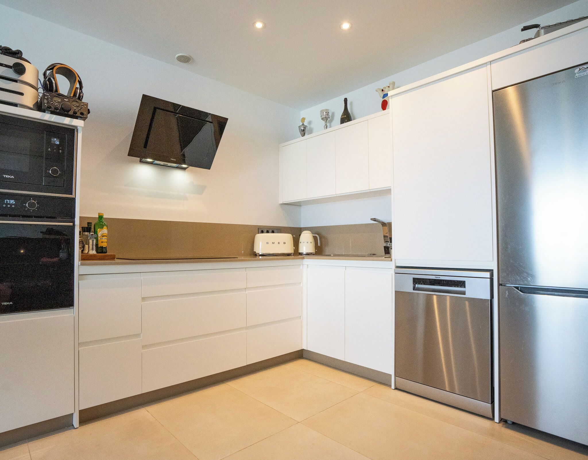 A modern kitchen with white cabinets, a stainless steel refrigerator, a microwave, and a toaster.