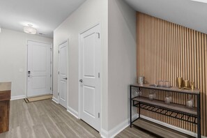 A hallway with two white doors, a wooden slatted wall, and a black metal console table with decorative items.