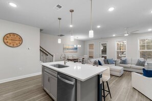 A modern kitchen with a central island, stainless steel appliances, and pendant lighting.