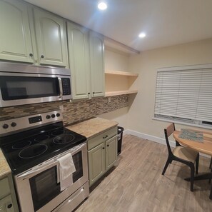 Compact kitchen area with a microwave, oven, and dining table.