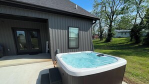 Ein Whirlpool neben einem Haus mit einer Schiebetür und einem Schild an der Veranda.
