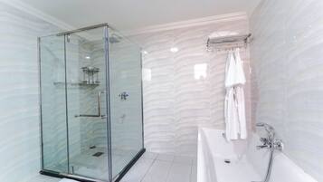 A modern bathroom with a glass-enclosed shower, a white bathtub, and a marble-patterned wall.