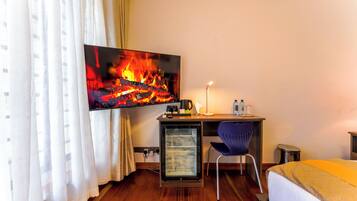 Une chambre d’hôtel comprenant un lit, un bureau avec un ordinateur, un téléviseur diffusant une image de cheminée et une chaise.