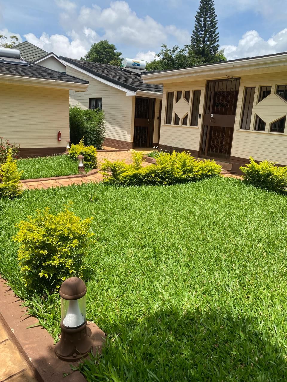 Zona residencial con dos casas, un césped cuidado y un camino.