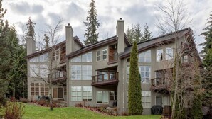 A multi-story residential building with a balcony, large windows, and a well-maintained lawn. - Elegant tranquility spacious 3BR golf course views close to Village & Lost Lake (Whistler)