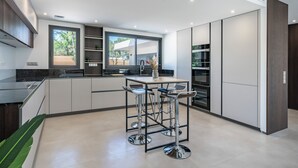 Een moderne keuken met een centraal eiland, barstoelen en geïntegreerde apparatuur.
