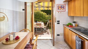 Eine Küche mit Holzausstattung, ein Essbereich mit Tisch und Stühlen sowie ein Blick auf einen Garten durch eine geöffnete Tür.
