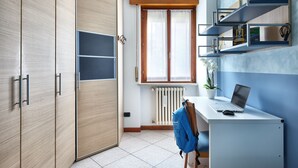 Ein modernes Schlafzimmer mit Kleiderschrank, Schreibtisch und Laptop sowie einem Heizkörper.