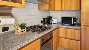 Eine Küche mit Holzausstattung, einem Gasherd, einer Mikrowelle, einer Kaffeemaschine und einem Toaster.