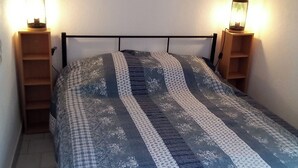 A bedroom with a bed, two bedside tables with lamps, a shelf above the bed, and a window with a star decoration.