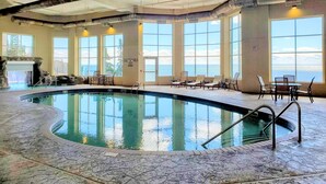 An indoor swimming pool with clear views of the ocean through large windows. - Lakefront Condo: Pool, Hot Tub, Deck, Fireplaces (Two Harbors)