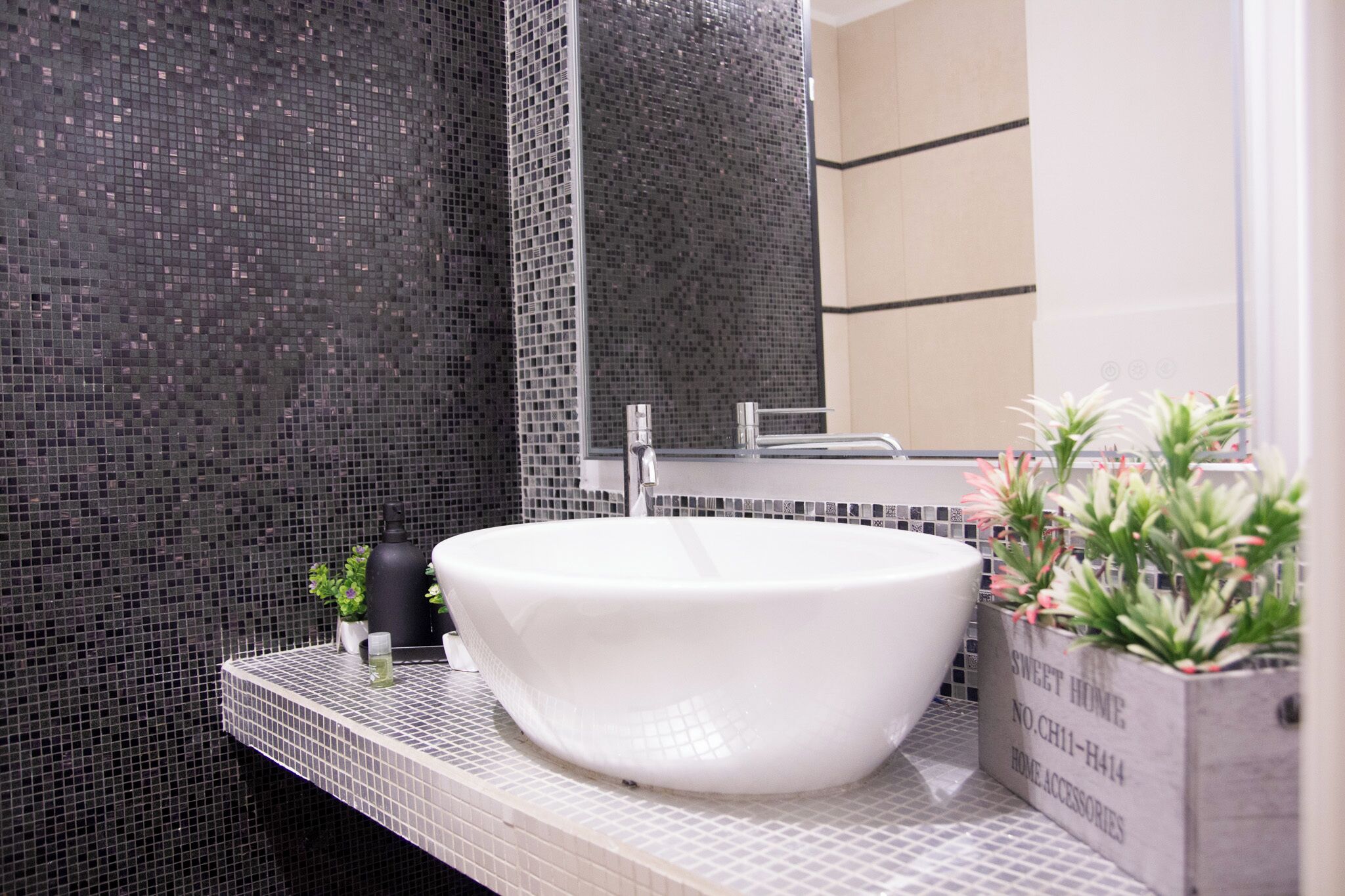 Un baño con lavamanos blanco, un espejo y un salpicadero de azulejos.