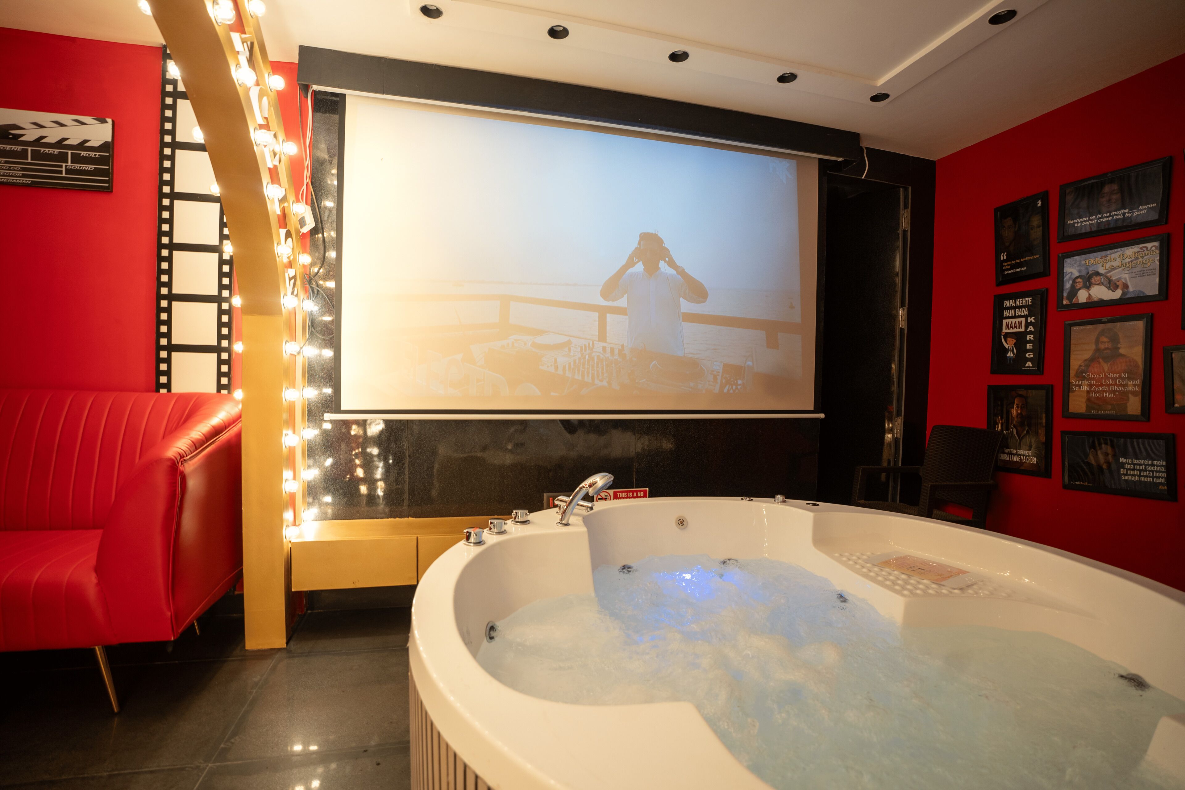 A room with a large bathtub, a red couch, and a wall with framed pictures.