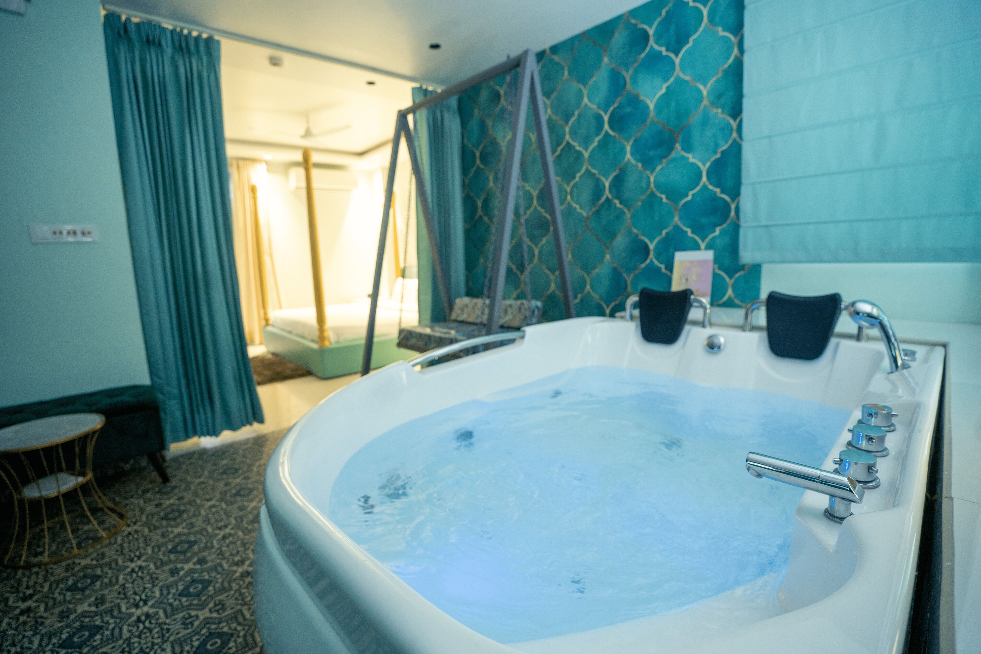 Eine große Badewanne mit Duschbrause, ein kleiner Tisch und eine Wand mit Muster.