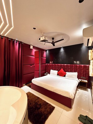 Une chambre moderne avec un grand lit, un ventilateur de plafond et un téléviseur intégré.