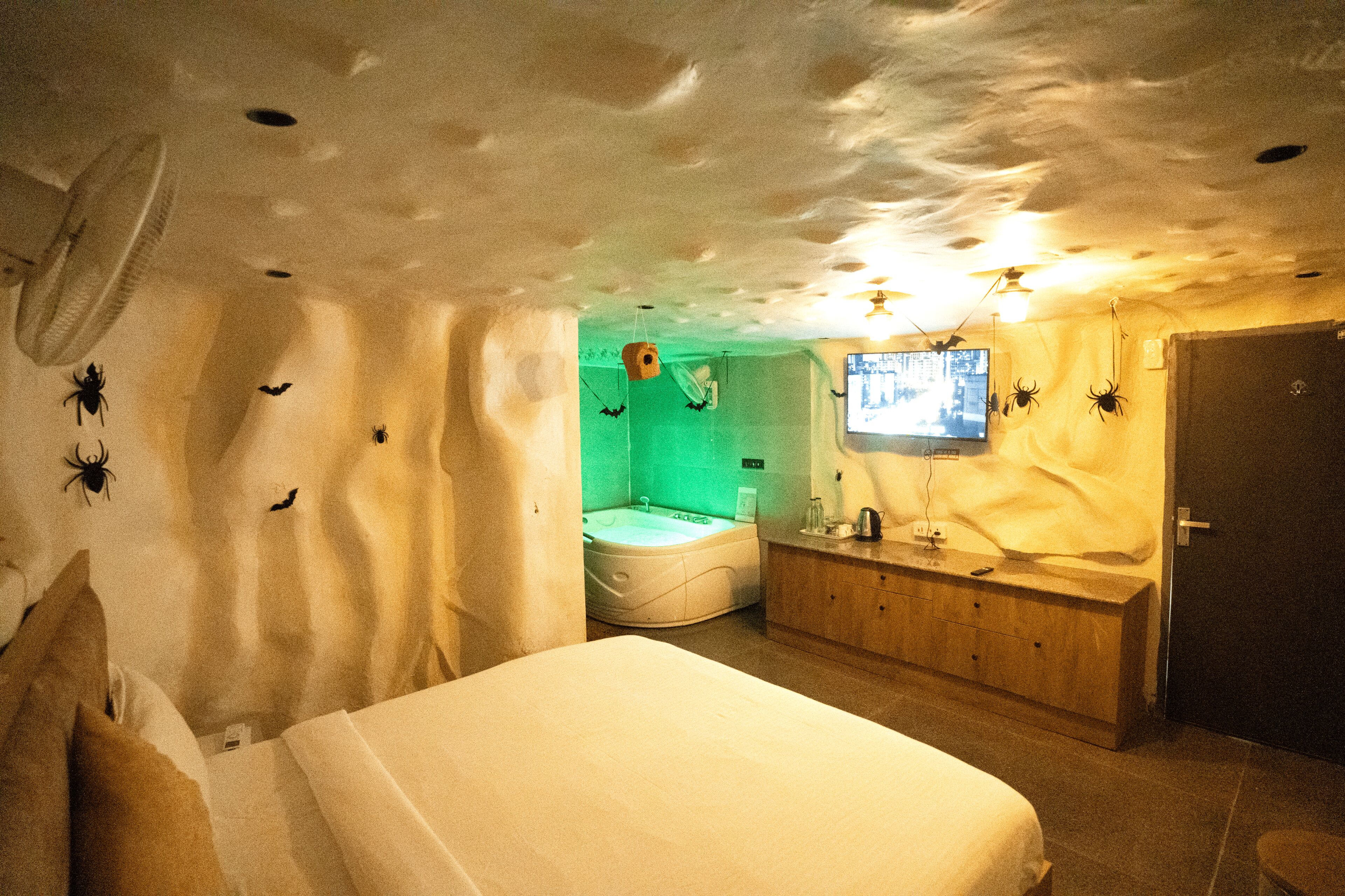 Una habitación con una cama, un aparador de madera, un televisor y un rincón iluminado de verde.