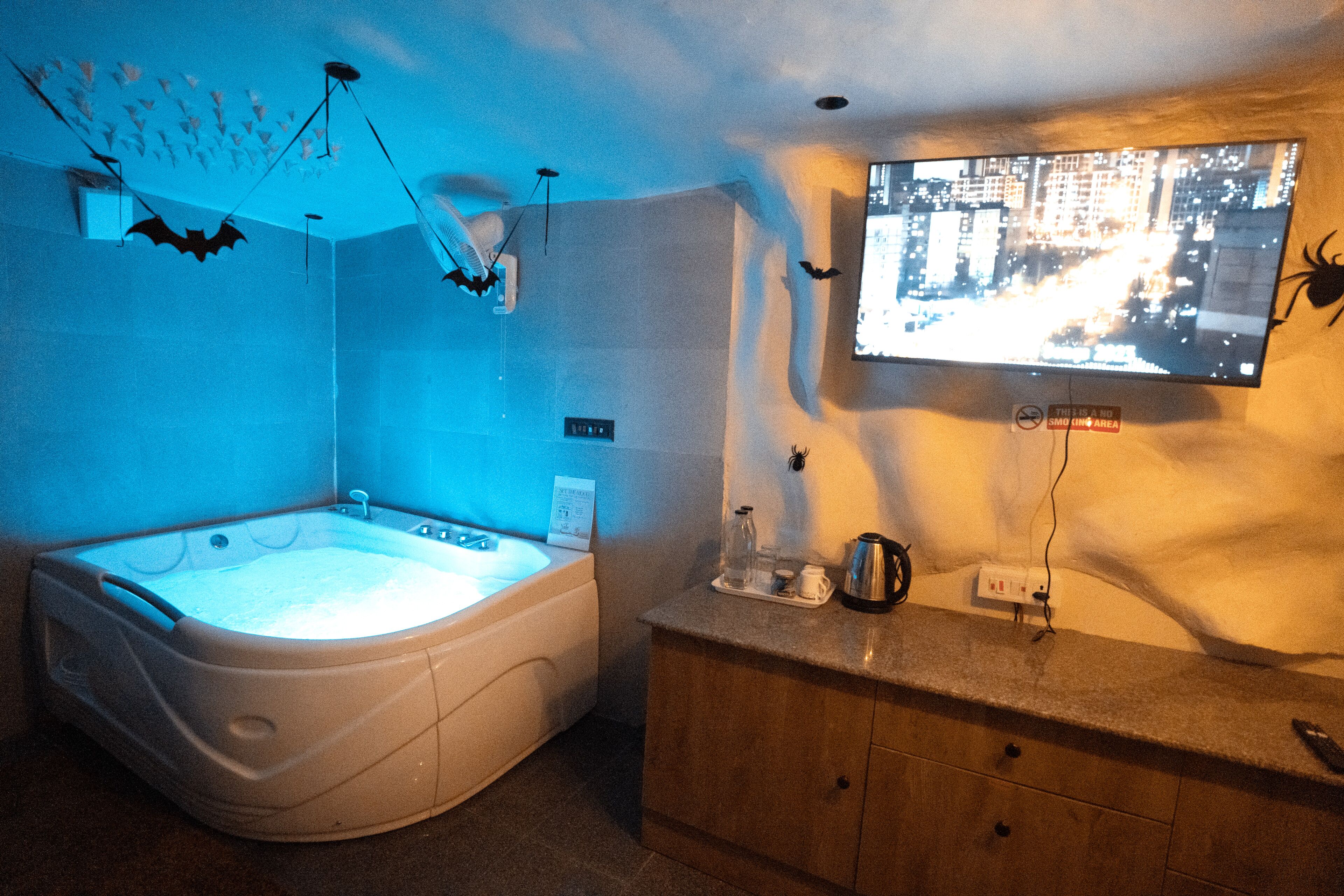 A bathroom with a bathtub, a vanity with a mirror, and a television mounted on the wall displaying a cityscape.