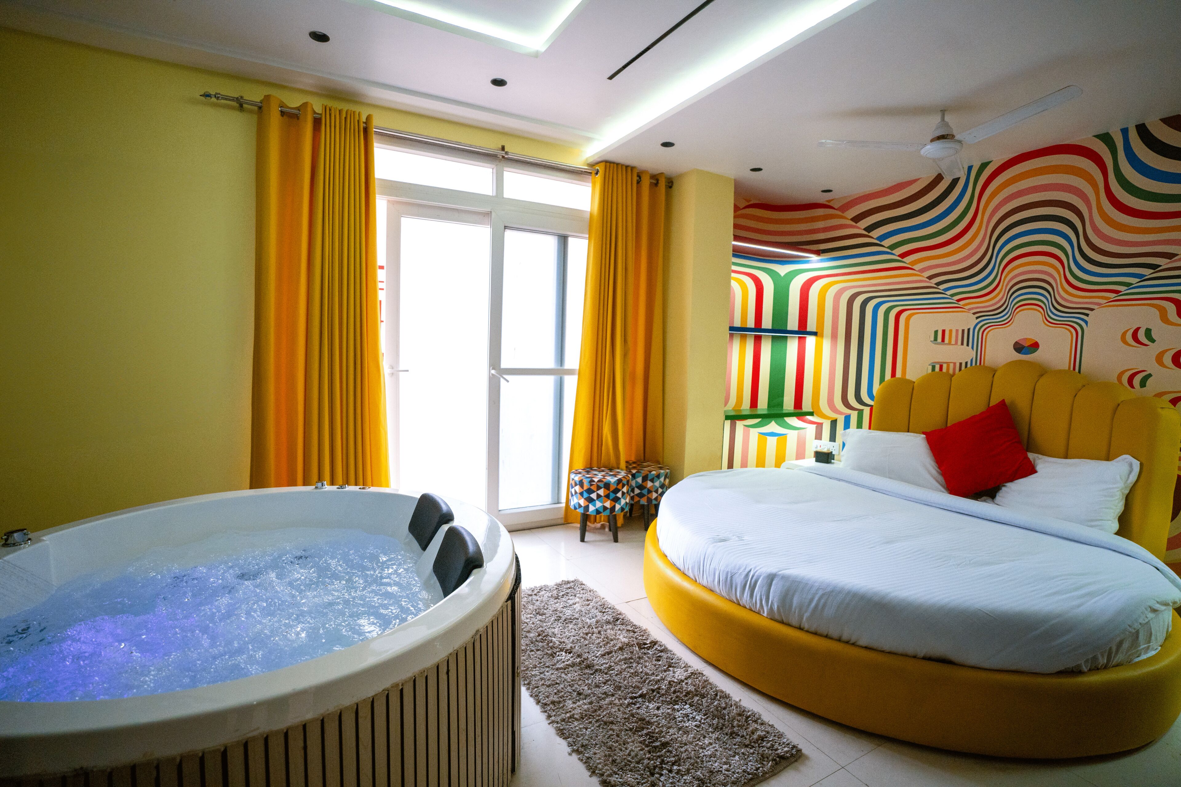 A room with a large bed, a bathtub, and a colorful wall.