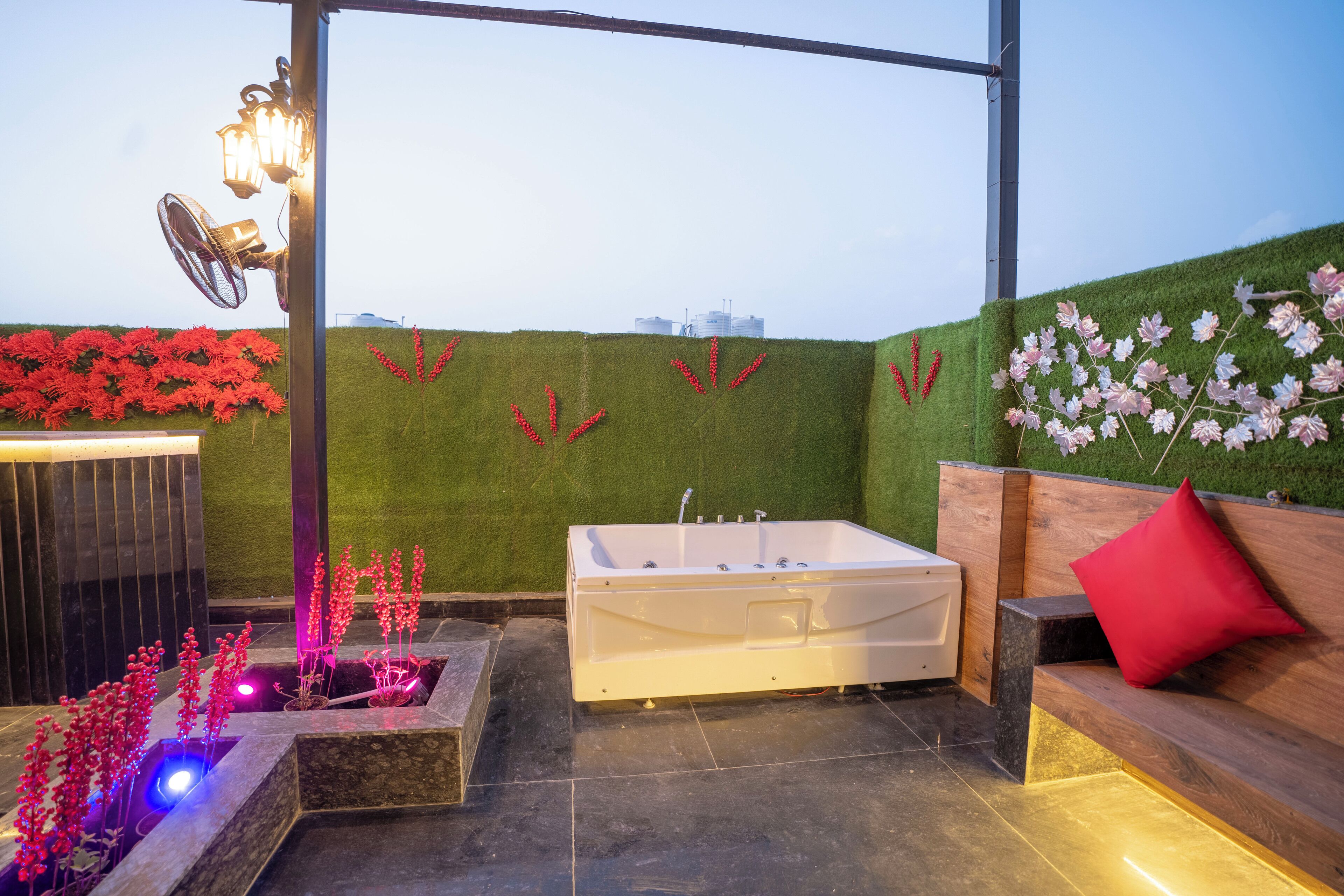 A rooftop terrace with a hot tub, seating area, and decorative plants.