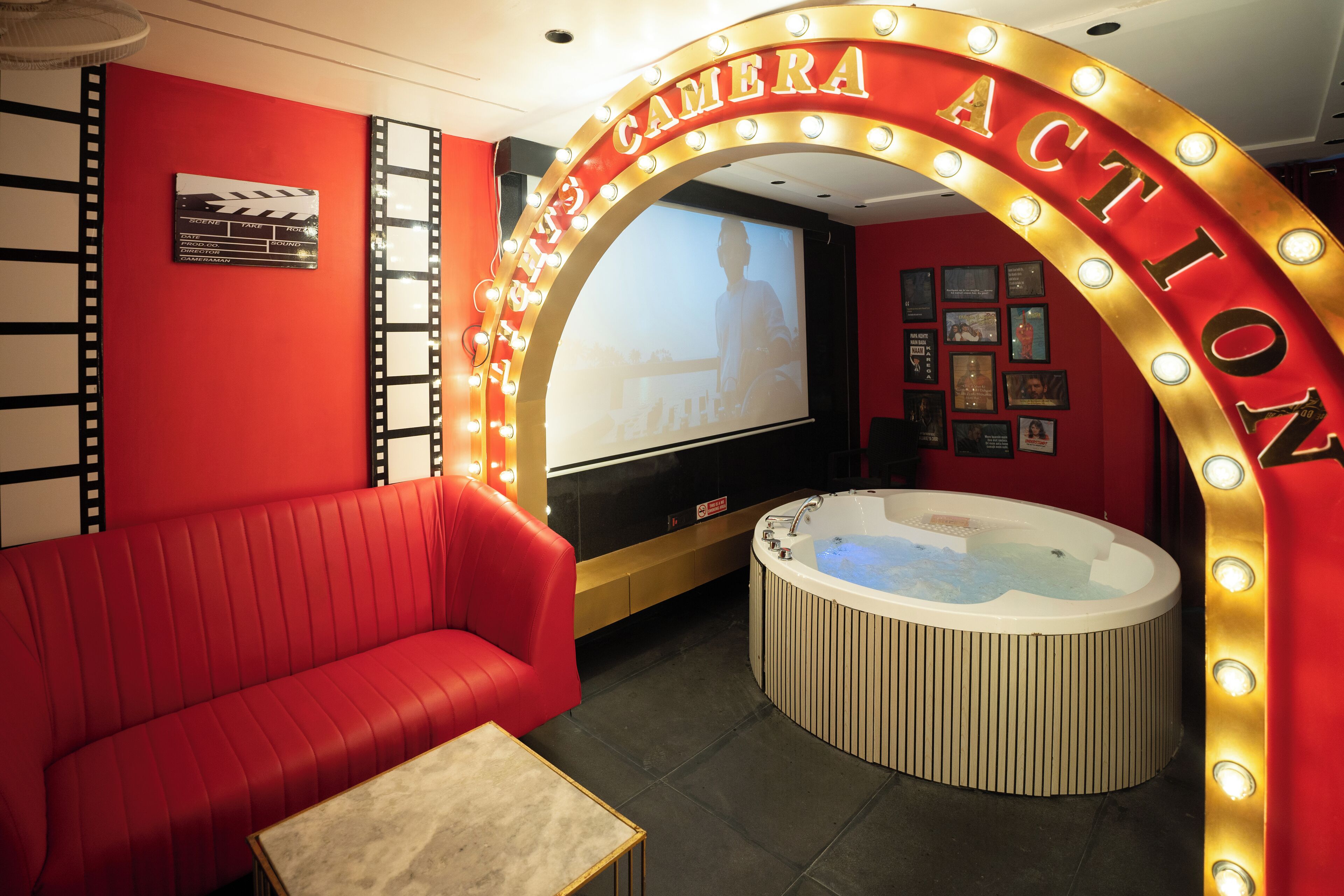 Una habitación roja con una pantalla grande, un sofá rojo y un jacuzzi.