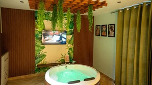A bathroom with a wooden floor, a bathtub, and a wooden ceiling with hanging plants. - Orsom Stays Sassy - Sector 42 (Gurugram)