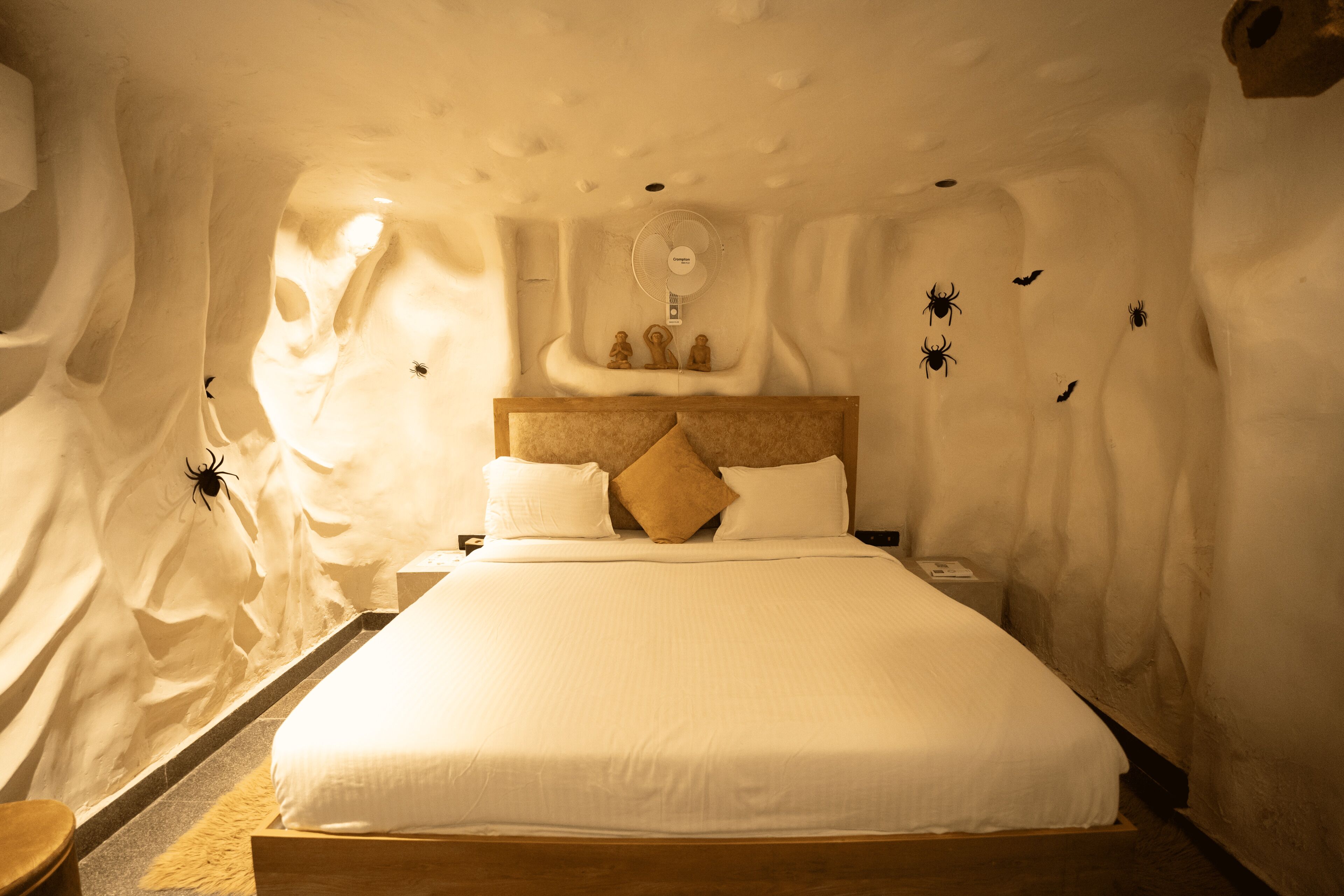 Quarto com uma cama, cabeceira de madeira e ventilador fixado na parede.