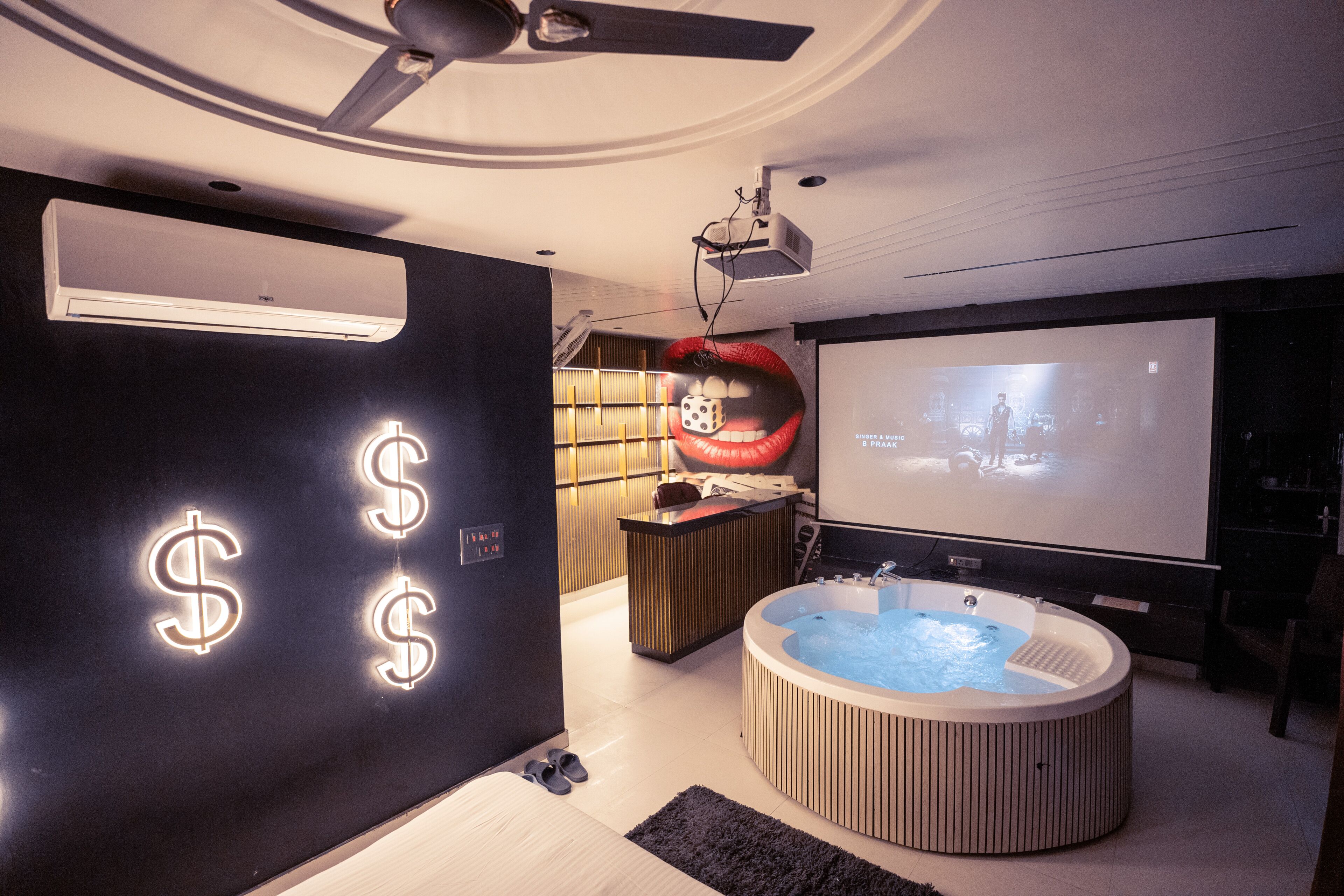 Een moderne kamer met een groot scherm, een jacuzzi en een plafondventilator.