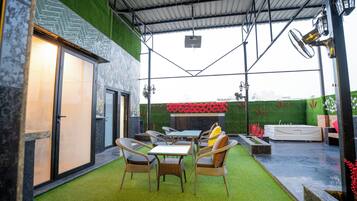 An outdoor patio with a dining table and chairs, a hot tub, and a fire pit.