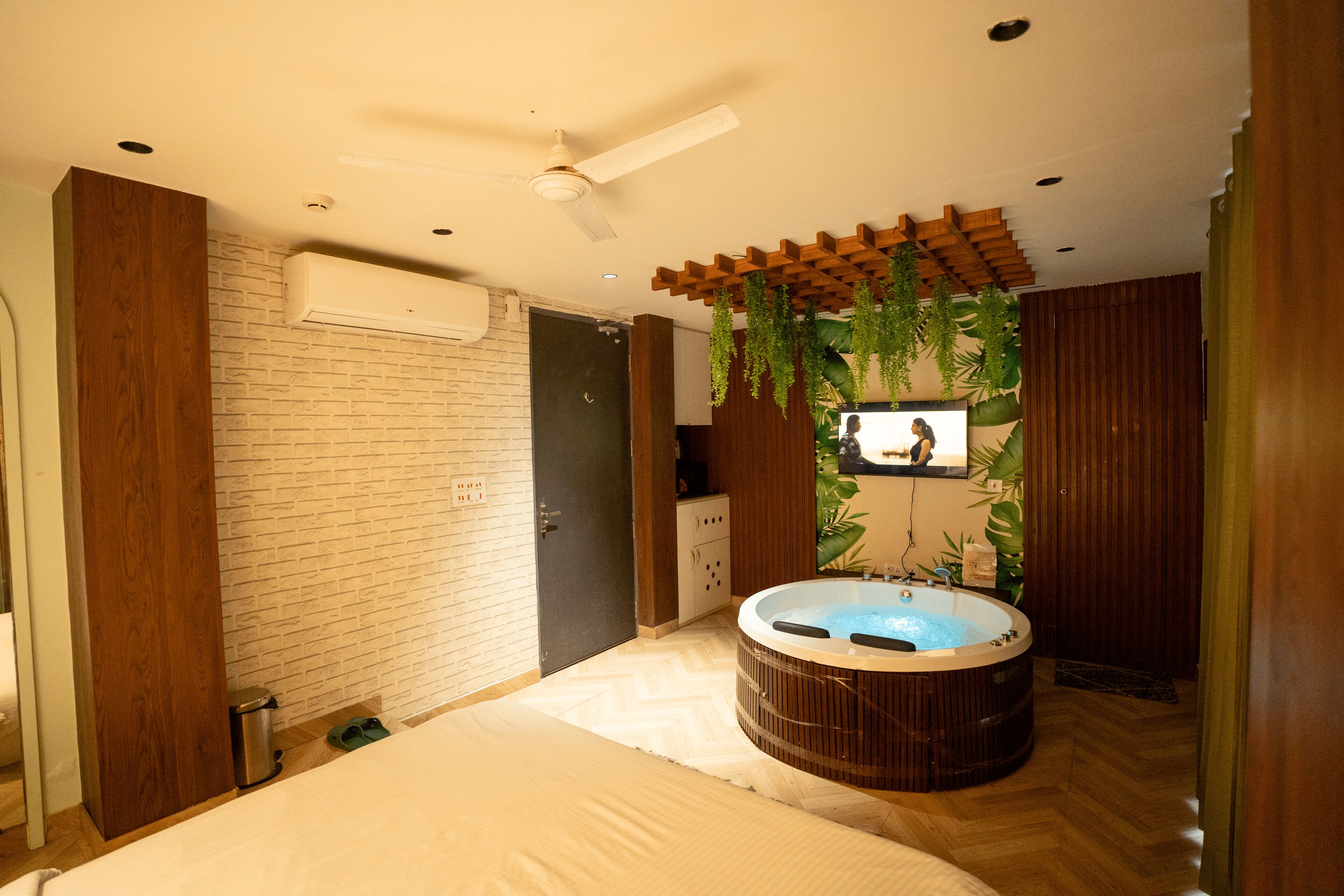 A modern bathroom with a large bathtub, wooden accents, and a brick wall.